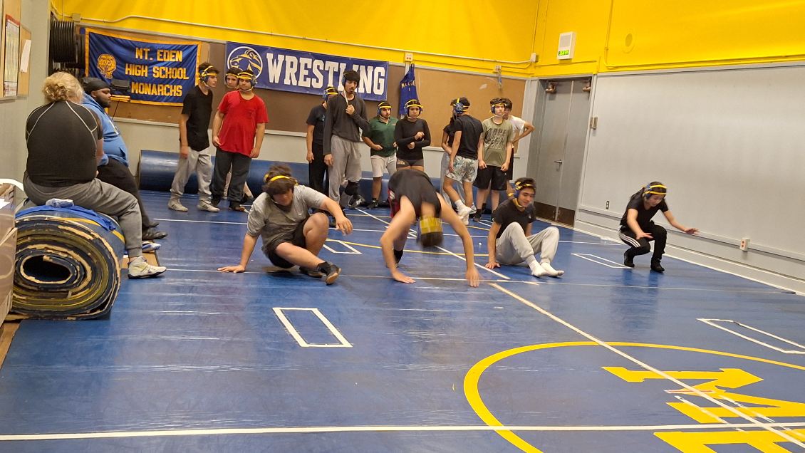 Wrestlers moving through drills.